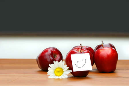 Delicious red apples on desk with blackboard in backgroundの写真素材