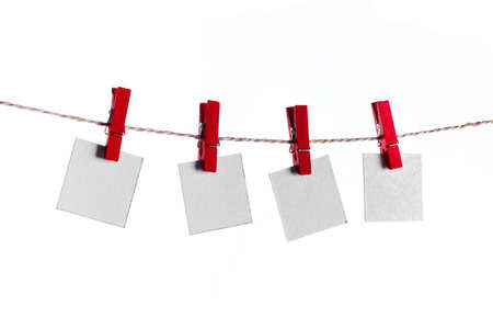 Set of four white blank paper notes held on a string with red clothespins isolated on white backgroundの写真素材