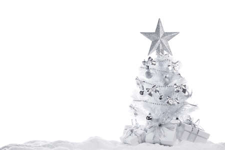 White christmas tree with silver decorations and gifts isolated on snow on white backgroundの写真素材