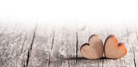 Two small wooden carved hearts on light wood background couple relationship Valentine day concept, white copy spaceの写真素材
