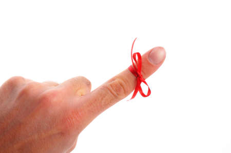 red bow on male finger showing reminder or dont forget concept in whiteの写真素材