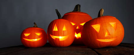 Halloween pumpkin head lanterns and burning candles on wooden backgroundの写真素材