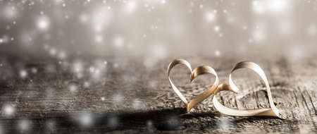Two golden ribbon hearts on wooden background with copy space for text, Valentines day conceptの写真素材