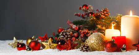 Christmas candles with traditional decorative stars , red baubles , pine cones and green branches on snowの写真素材