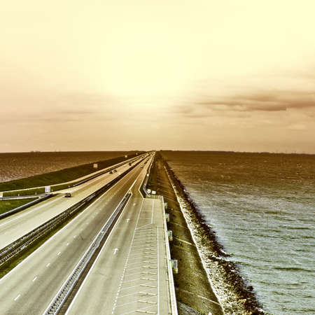 Sunset over Modern Highway on the Protective Dam in Netherlands, Vintage Style Toned Pictureの写真素材