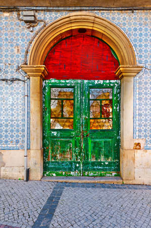 Shabby Wooden Door in the Wall Decorated with Portuguese Ceramic Tilesの写真素材