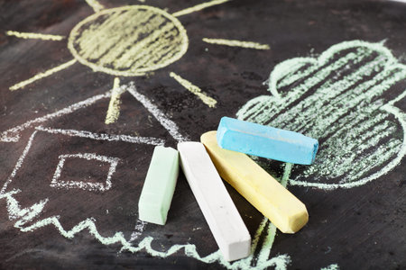 House, sun and tree drawing and chalks on a blackboard
