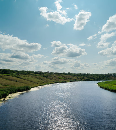 light clouds in blue sky over river with reflections