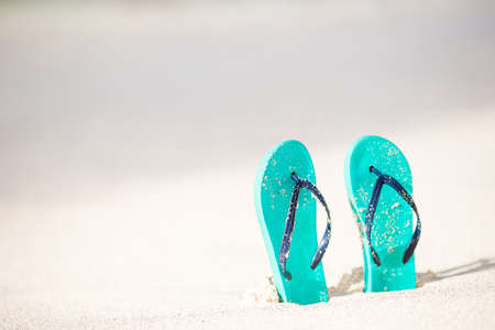 Summer holiday beach background with flip flops on a tropical beach. Slippers on a sand with copyspace.の写真素材