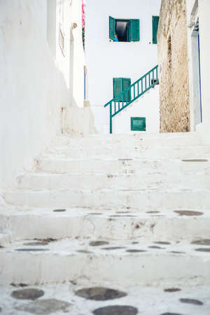 The narrow streets of the island with blue balconies, stairs and flowers in Greece.の写真素材