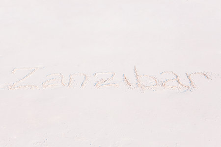 Word handwritten on sandy beach with soft ocean wave on backgroundの写真素材