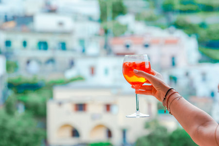 Glass with Spritz Aperol alcohol drink background of beautiful old italian village on Amalfi coastの写真素材