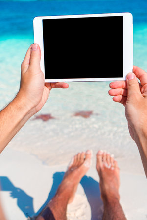 Man with tablet on the beach workingの写真素材
