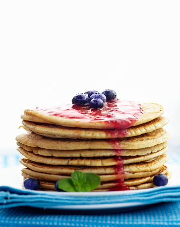 Breakfast food. Pancakes with jam and blueberries isolated on white.