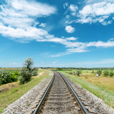 railway in green landscape and white clouds in blue skyの写真素材