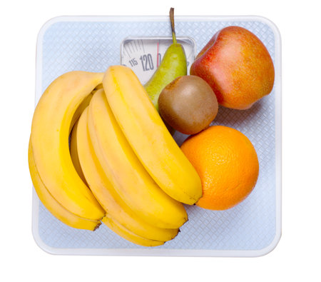 Fruits on a scales isolated over whiteの写真素材