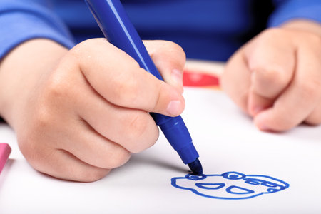 Child's hand drawing a car with blue felt penの写真素材