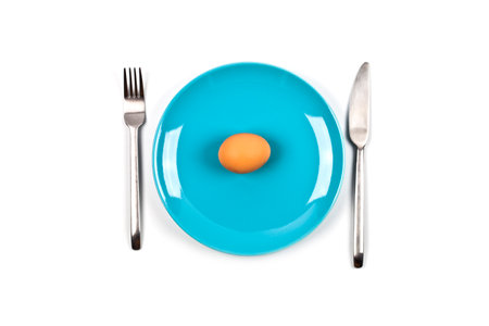 Fresh chicken boiled egg on blue plate, fork and knife on white background. Top view image.の写真素材