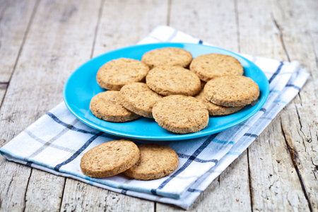 Fresh baked oat cookies on blue ceramic plate on linen napkin on rustic wooden table background.の写真素材