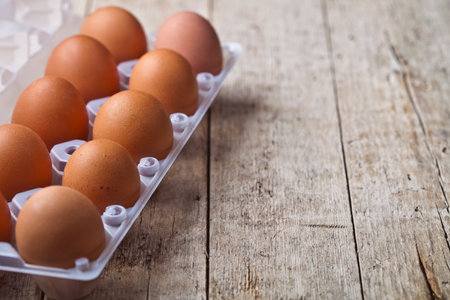 Fresh chicken eggs on plastic container on rustic wooden table background. With copy space.の写真素材