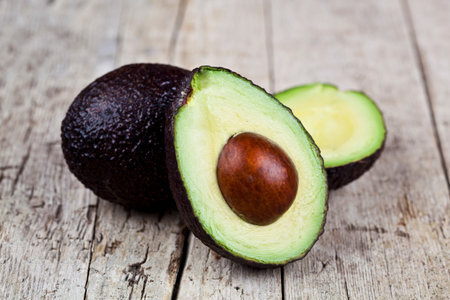 Fresh organic avocado on old wooden table background. Fresh avocado halves on rustic wooden...