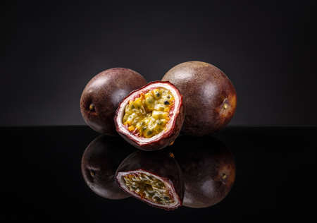 Whole and half passion fruits (maracuya) on black backgroundの写真素材