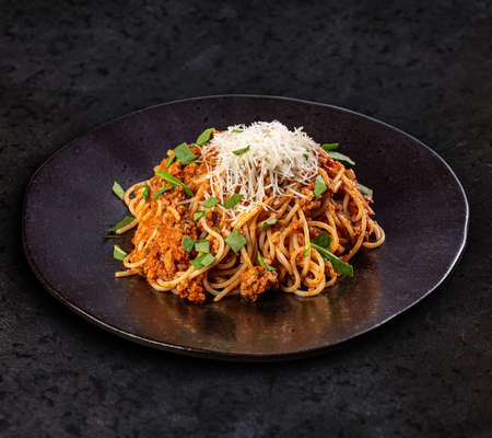 Italian pasta bolognese. Delicious spaghetti bolognese served on a black plateの写真素材