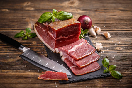 Slices of prosciutto on old wooden background