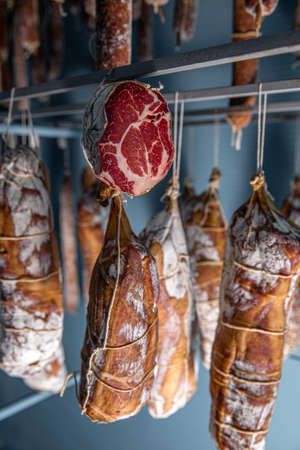 Air dried pork sausage and smoked meat hanging in warehouseの写真素材