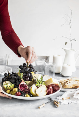 Woman preparing a cheese platter and breadの素材