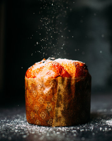 A muffin wrapped in paper and sprinkled with powdered sugar.の素材