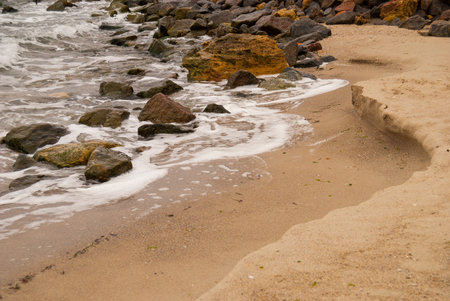 sea waves washed stones lying on a sandy beach