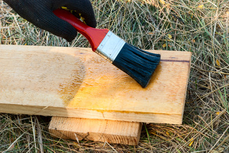 painter holding a brush and varnishes wooden structure
