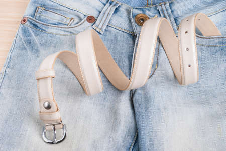 women's jeans on the table and collapsed beltの写真素材