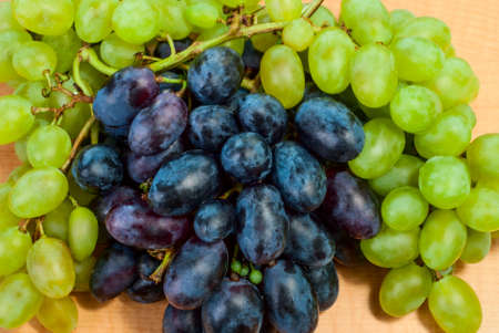 On the table are ripe bunches of white and black grapesの写真素材