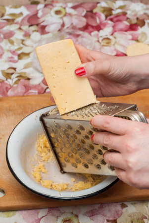 woman in the kitchen prepares grated cheeseの写真素材
