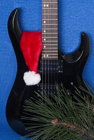 black electric guitar and santa hat on a blue background