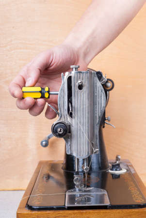 repairman unscrews the screw on an old sewing machineの写真素材