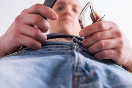 young man fastened the belt on his jeansの写真素材