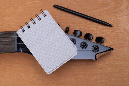 blank notebook on a black electric guitar strings