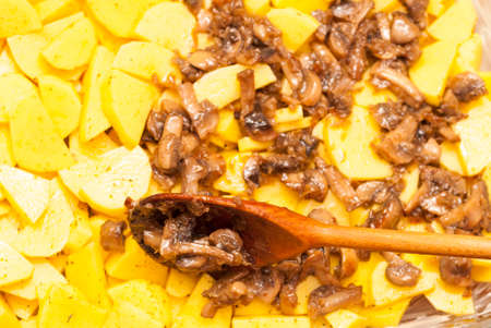 cook puts a wooden spoon roasted mushrooms potatoesの写真素材
