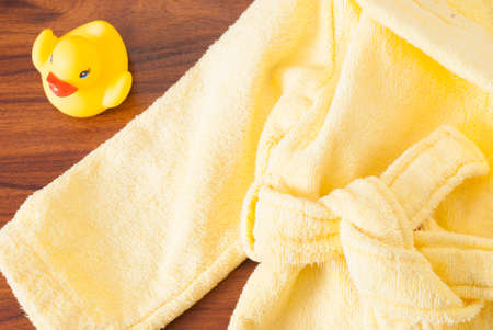 rubber ducky and a children's bathrobe on the tableの写真素材