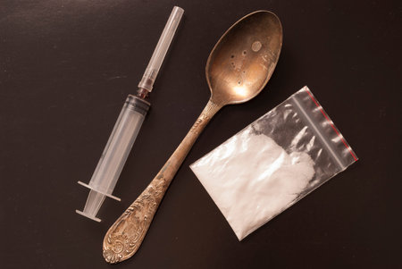 a syringe, a spoon and a bag of white powder