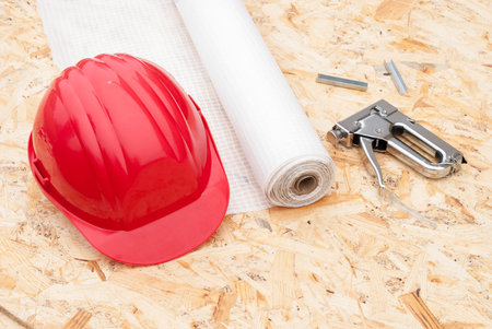 roll a vapor barrier, helmet and a stapler in the background OSB