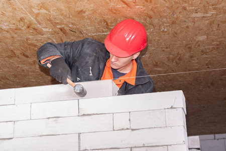 bricklayer puts a wall of aerated concrete blocks