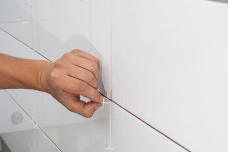 master laying a white ceramic tile on wallの写真素材