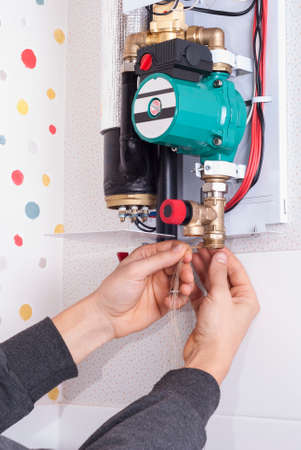 plumber pulls tow on the threaded connection of the electric boilerの写真素材
