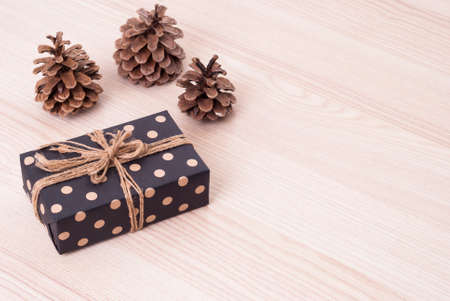 gift in box and pine cones on a tableの写真素材