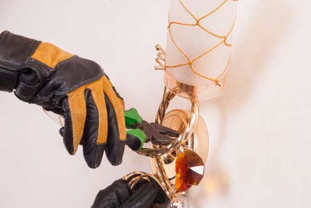 electrician with pliers in his hand repairing a sconceの写真素材