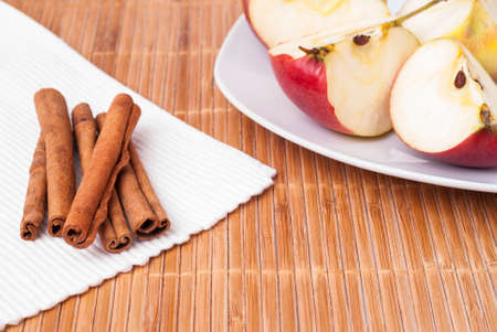 cinnamon sticks and apple slices on a bamboo table clothの写真素材